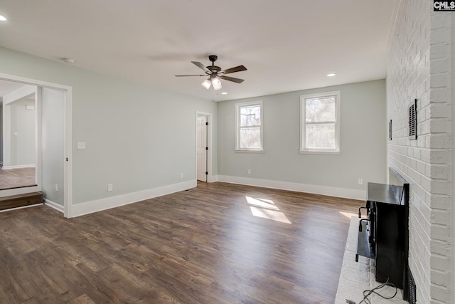 unfurnished living room featuring dark hardwood / wood-style flooring, a brick fireplace, and ceiling fan