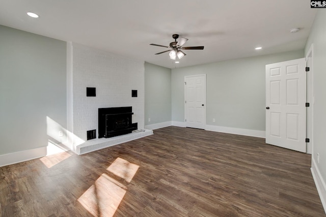 unfurnished living room featuring ceiling fan, a fireplace, and dark hardwood / wood-style floors