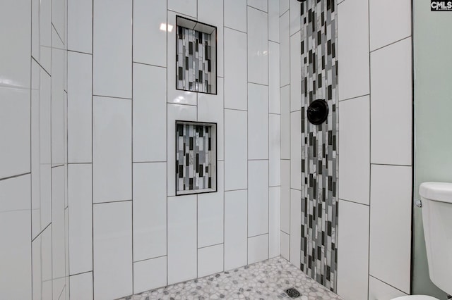 bathroom featuring toilet and tiled shower