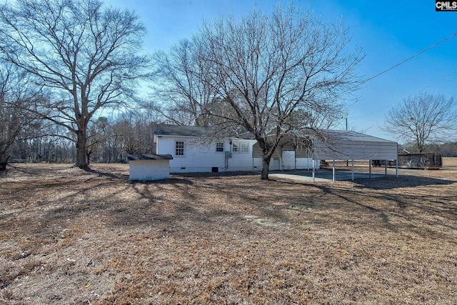 rear view of property with a carport and a storage unit