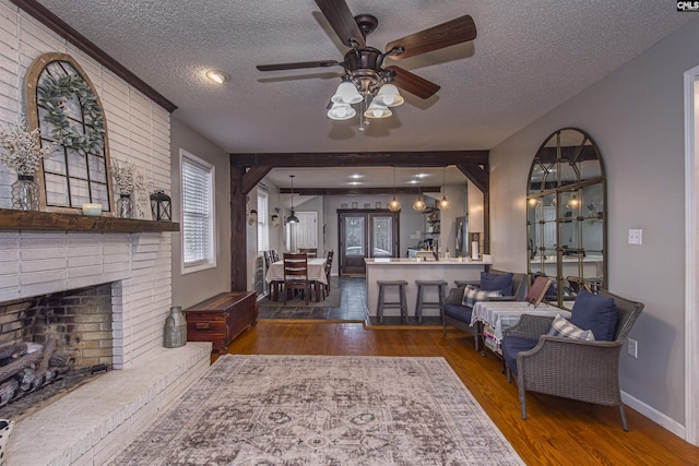 living room with dark hardwood / wood-style flooring, ceiling fan, a fireplace, and a textured ceiling