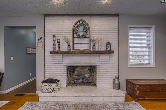 living room with a brick fireplace, hardwood / wood-style flooring, and a textured ceiling