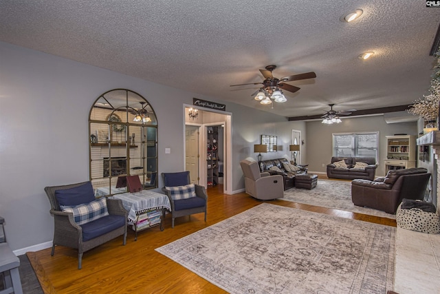 living room with hardwood / wood-style flooring, ceiling fan, and a textured ceiling