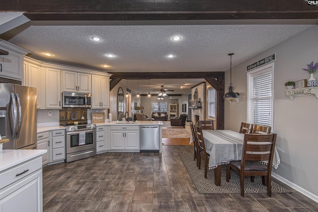 kitchen with stainless steel appliances, decorative light fixtures, kitchen peninsula, and a textured ceiling