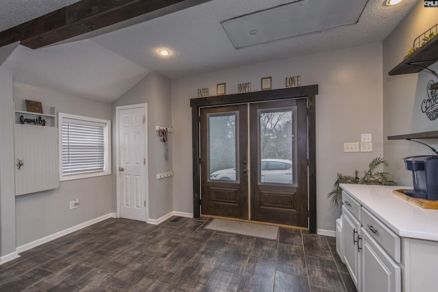 foyer entrance featuring dark hardwood / wood-style flooring, lofted ceiling, french doors, and a textured ceiling