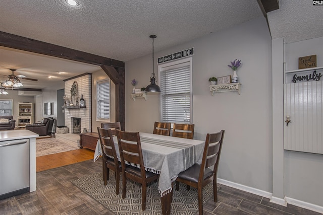 dining room with a brick fireplace, dark wood-type flooring, and a textured ceiling