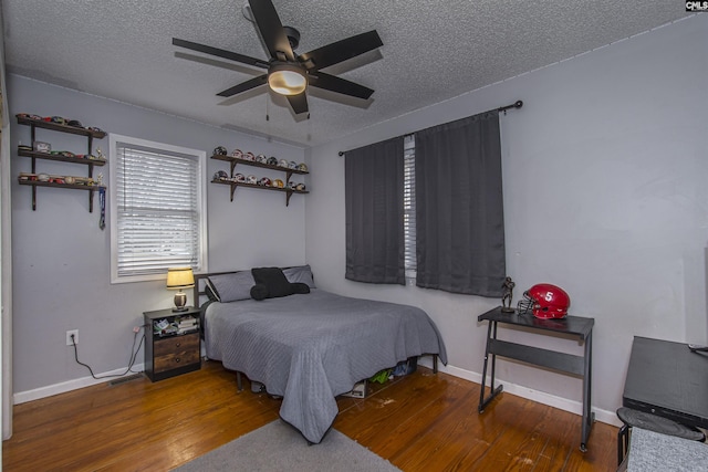 bedroom with ceiling fan, hardwood / wood-style flooring, and a textured ceiling