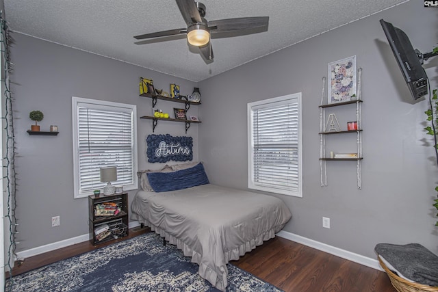 bedroom with ceiling fan, dark wood-type flooring, and a textured ceiling