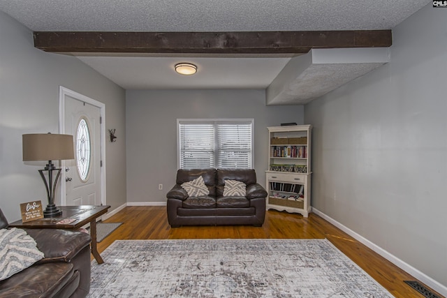 living room featuring hardwood / wood-style floors, beam ceiling, and a textured ceiling