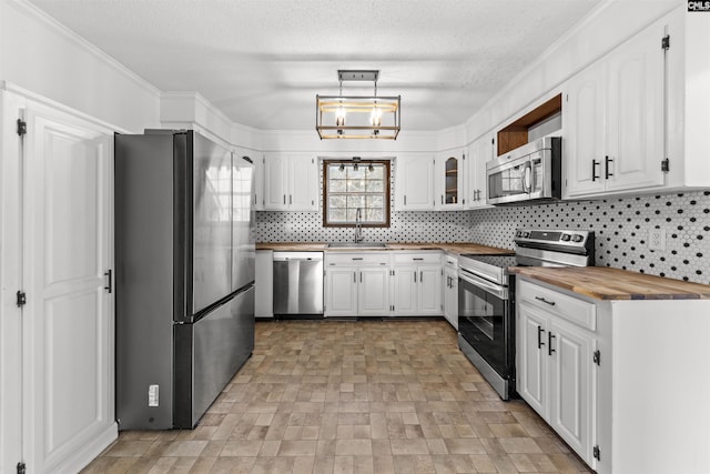 kitchen featuring stainless steel appliances, butcher block counters, sink, and white cabinets