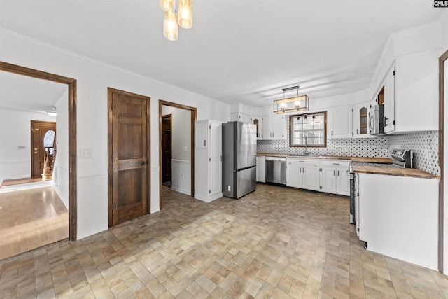 kitchen featuring white cabinetry, an inviting chandelier, tasteful backsplash, decorative light fixtures, and stainless steel appliances