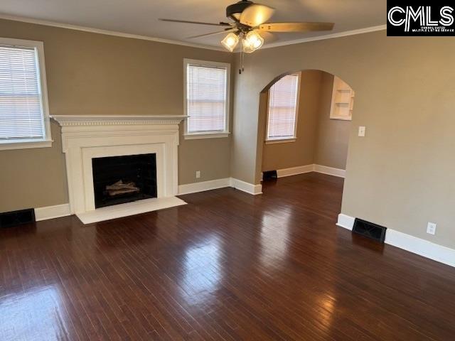 unfurnished living room with ornamental molding, dark hardwood / wood-style floors, and ceiling fan