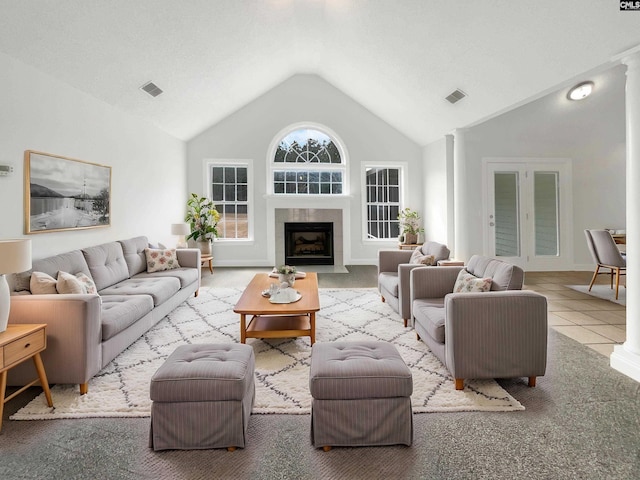 tiled living room with a fireplace, high vaulted ceiling, and ornate columns