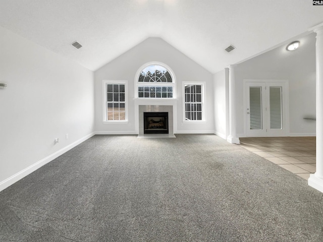 unfurnished living room with a fireplace, carpet floors, decorative columns, and vaulted ceiling