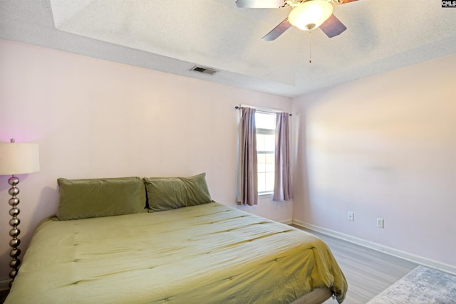 bedroom with ceiling fan, wood-type flooring, and a textured ceiling