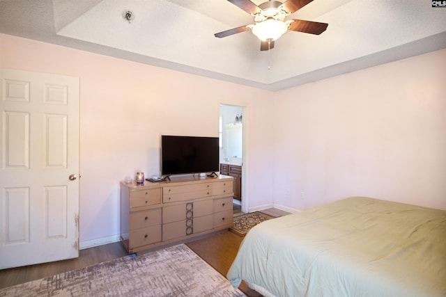 bedroom featuring ceiling fan, light wood-type flooring, and a tray ceiling