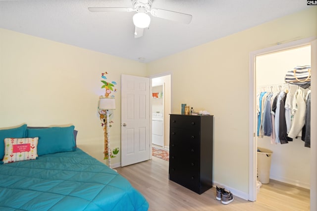 bedroom with washer / clothes dryer, a walk in closet, light hardwood / wood-style floors, and a closet