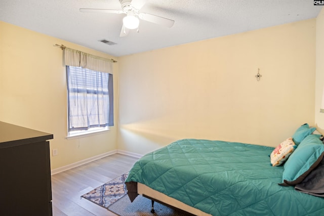 bedroom featuring ceiling fan, hardwood / wood-style floors, and a textured ceiling