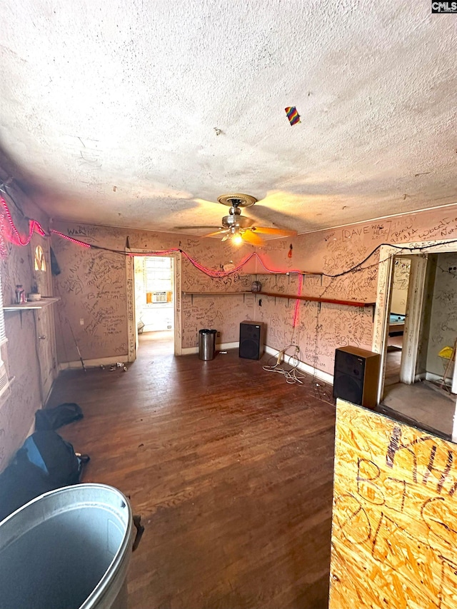 living room featuring dark wood-type flooring, ceiling fan, and a textured ceiling