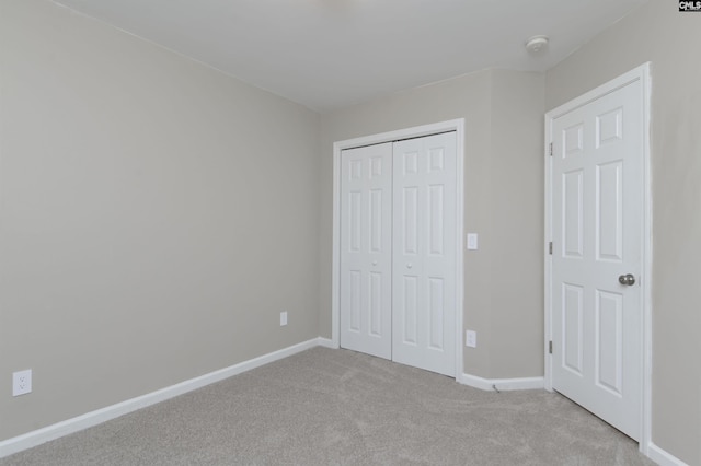 unfurnished bedroom with light carpet and a closet