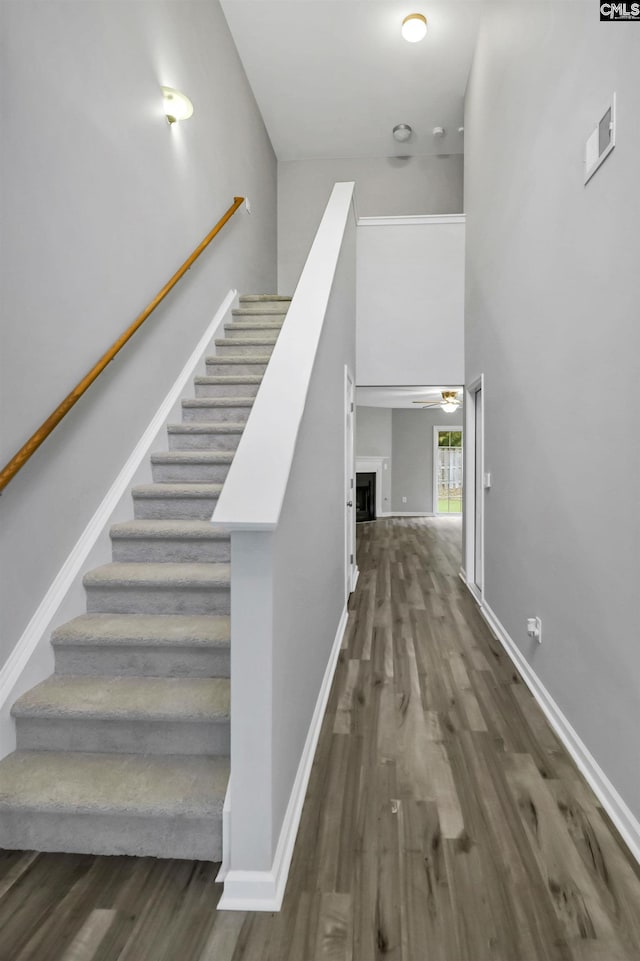 stairs featuring hardwood / wood-style flooring, a high ceiling, and ceiling fan