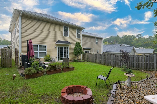 rear view of property with a yard and a fire pit