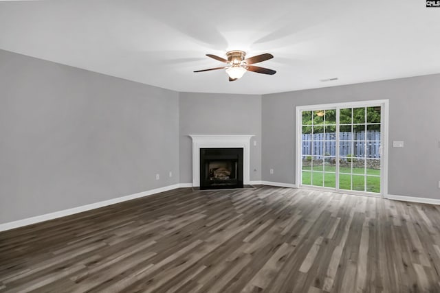 unfurnished living room featuring dark wood-type flooring and ceiling fan