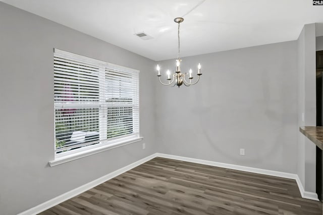 unfurnished dining area with dark hardwood / wood-style flooring and an inviting chandelier