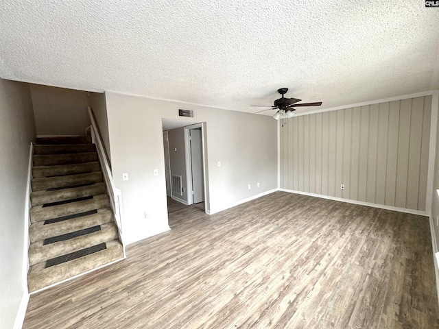 unfurnished living room with ceiling fan, hardwood / wood-style floors, and a textured ceiling