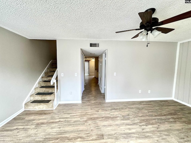 unfurnished room with ceiling fan, a textured ceiling, and light wood-type flooring