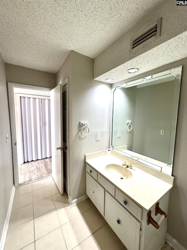 bathroom featuring tile patterned flooring, vanity, and a textured ceiling