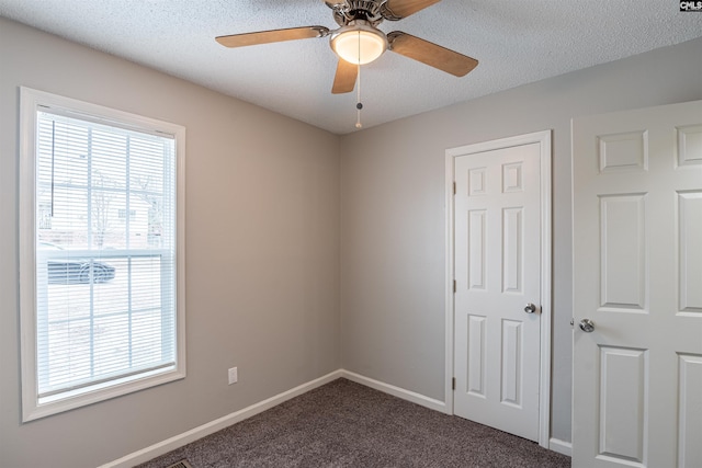 carpeted empty room featuring ceiling fan and a textured ceiling