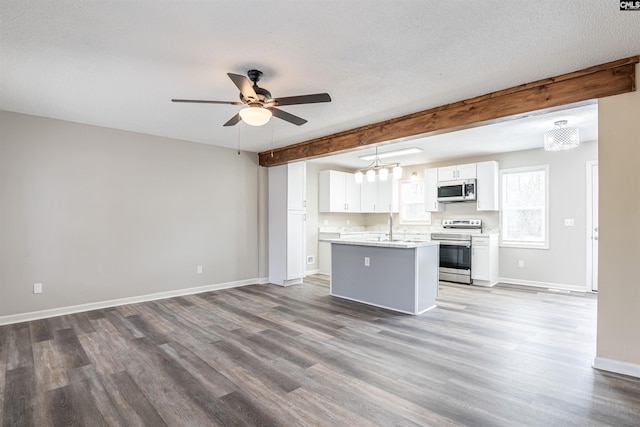 kitchen with hanging light fixtures, a kitchen island, stainless steel appliances, beam ceiling, and white cabinets