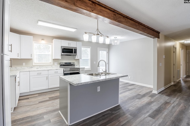 kitchen with pendant lighting, sink, stainless steel appliances, an island with sink, and white cabinets