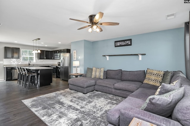 living room with dark wood-type flooring and ceiling fan