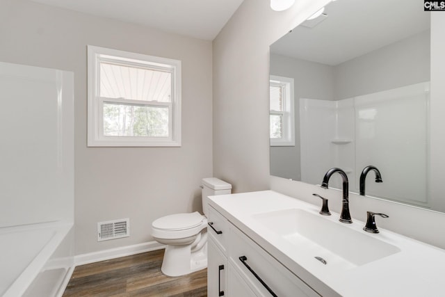 bathroom with wood-type flooring, toilet, vanity, and a wealth of natural light