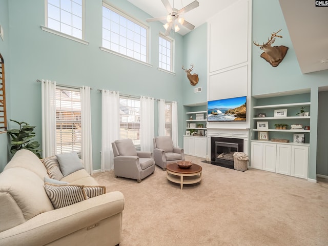 carpeted living room featuring ceiling fan, built in shelves, and a healthy amount of sunlight