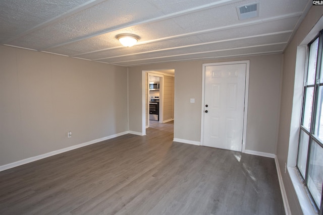 spare room with dark hardwood / wood-style floors and a textured ceiling