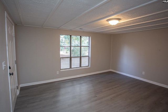 empty room with dark hardwood / wood-style floors and a textured ceiling