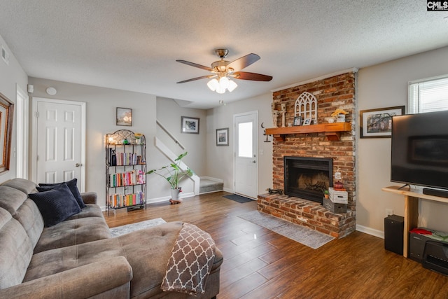 living room with ceiling fan, a fireplace, dark hardwood / wood-style floors, and a textured ceiling