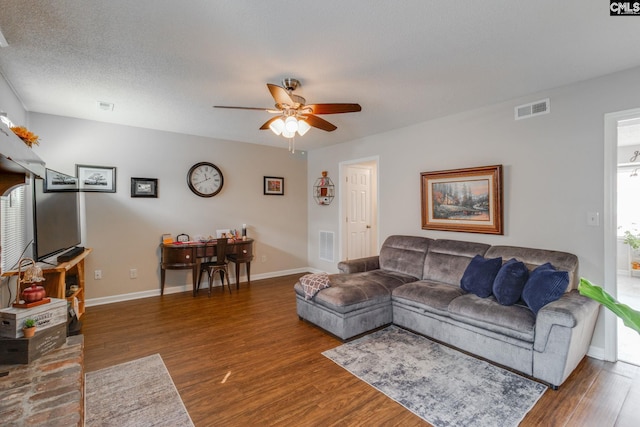 living room with ceiling fan, dark hardwood / wood-style floors, and a textured ceiling