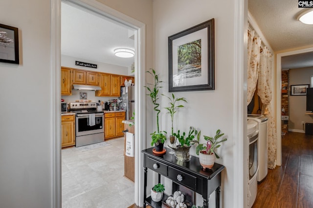 kitchen with stainless steel appliances, light hardwood / wood-style flooring, washer and dryer, and a textured ceiling