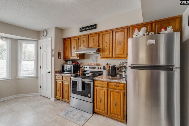 kitchen featuring light stone counters, a textured ceiling, and appliances with stainless steel finishes