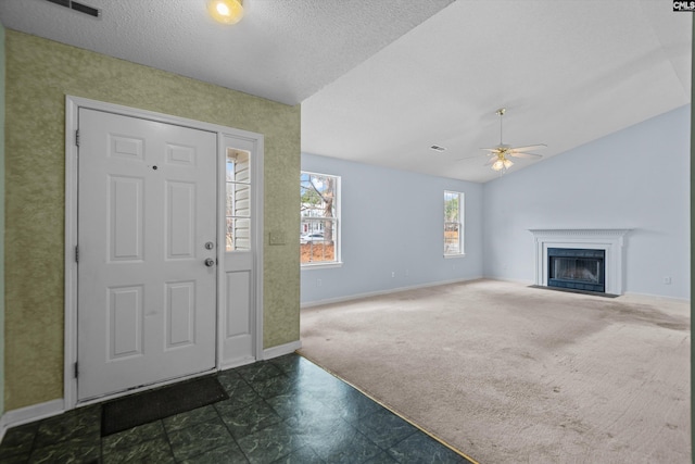 carpeted entrance foyer with lofted ceiling, a textured ceiling, and ceiling fan