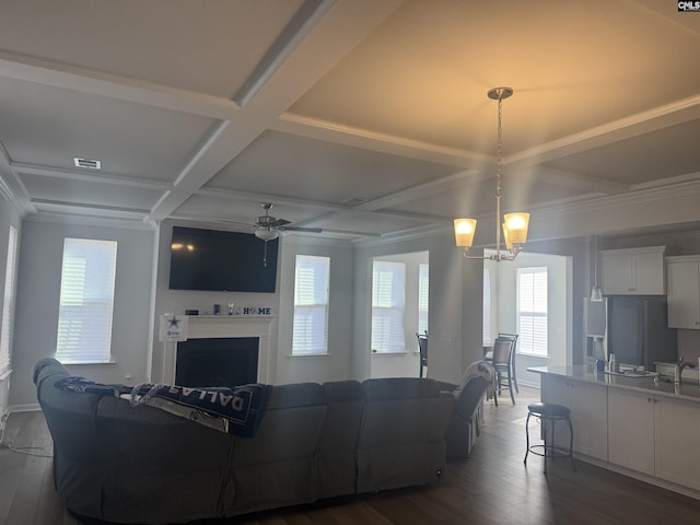 living room featuring coffered ceiling, ornamental molding, dark hardwood / wood-style floors, beam ceiling, and ceiling fan with notable chandelier