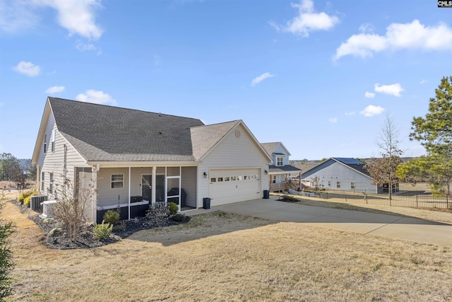 view of front of home with a garage, central AC, and a front lawn