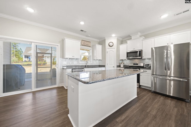 kitchen with appliances with stainless steel finishes, a center island, dark stone countertops, and white cabinets