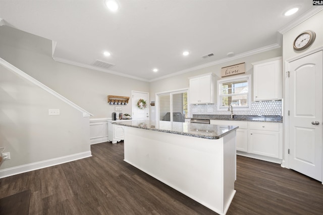 kitchen featuring dark stone countertops, dark hardwood / wood-style floors, a center island, and white cabinets