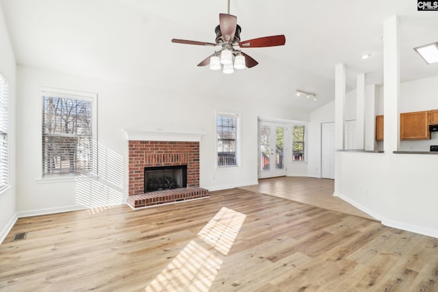 unfurnished living room featuring ceiling fan, a fireplace, vaulted ceiling, and light hardwood / wood-style flooring