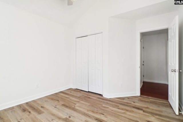 unfurnished bedroom featuring lofted ceiling, light hardwood / wood-style flooring, a closet, and ceiling fan